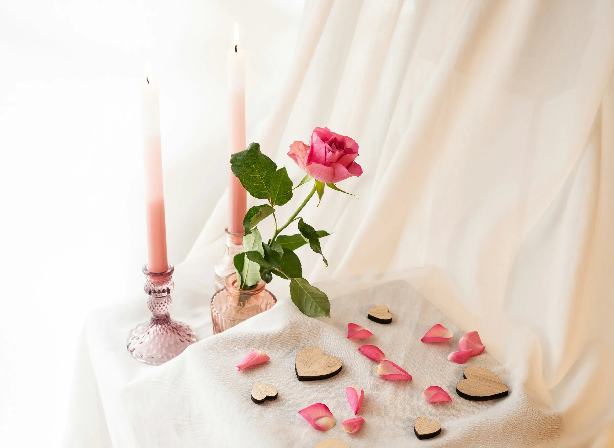 Velas, rosa e pétalas sobre a mesa