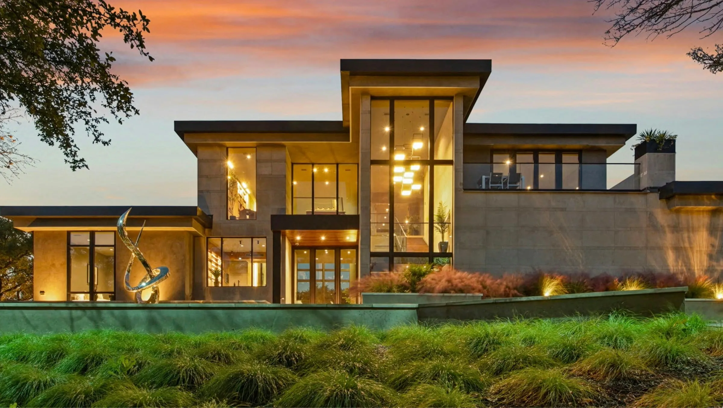 Fachada da Casa Jardim Europa ao entardecer, com as luzes acesas e o jardim em primeiro plano