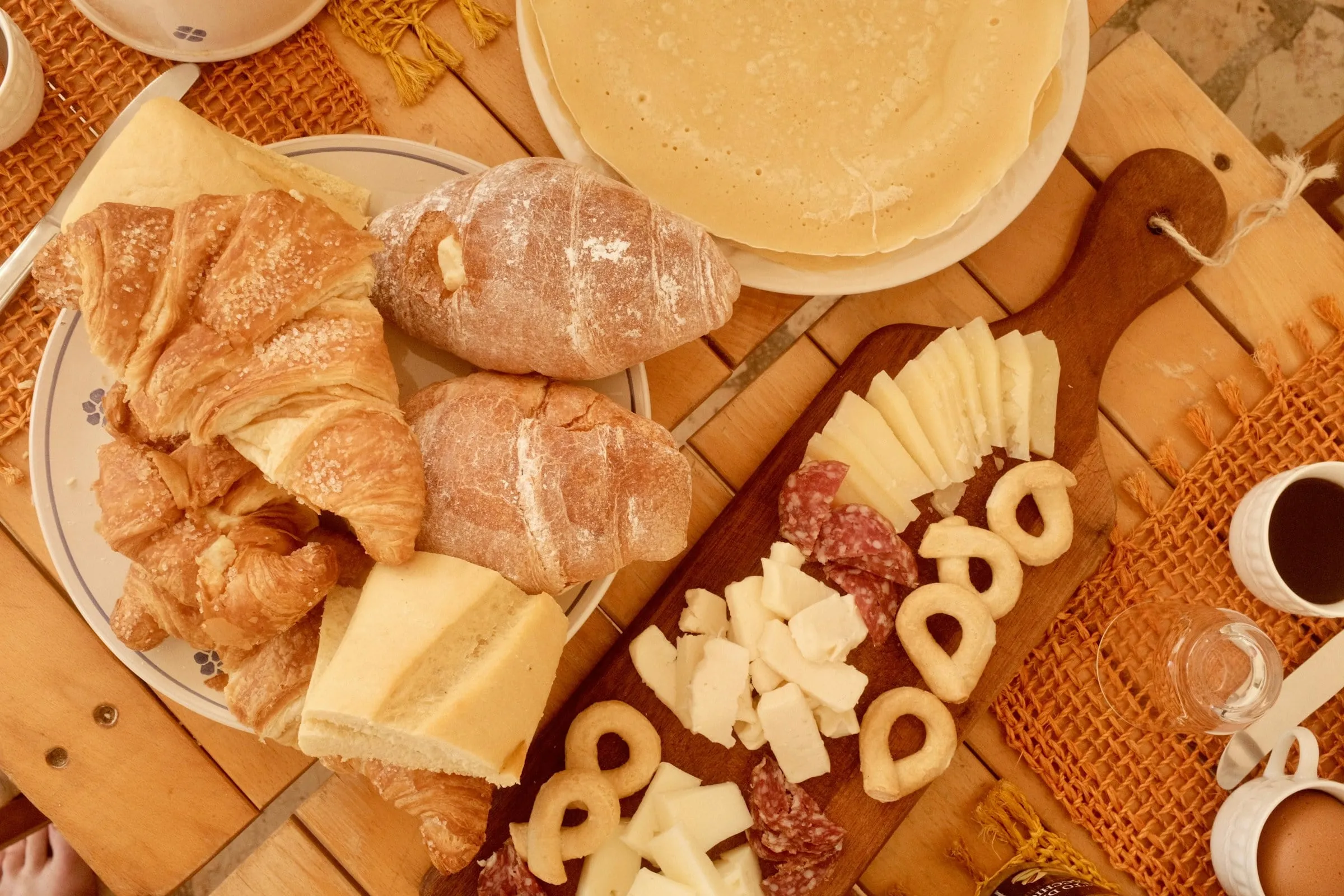 Mesa farta de café colonial com pães, queijos e frios