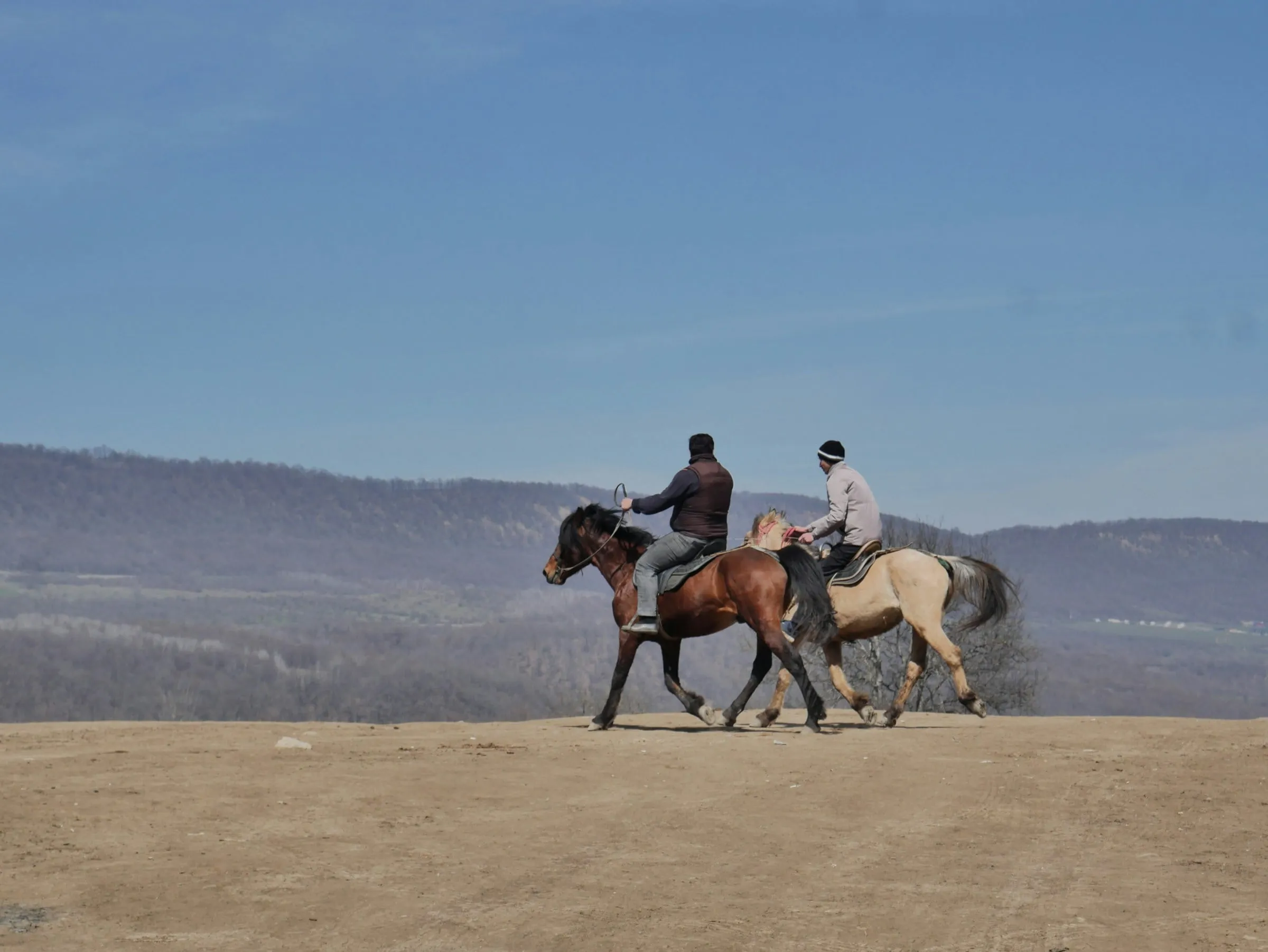 Duas pessoas cavalgando pelos campos