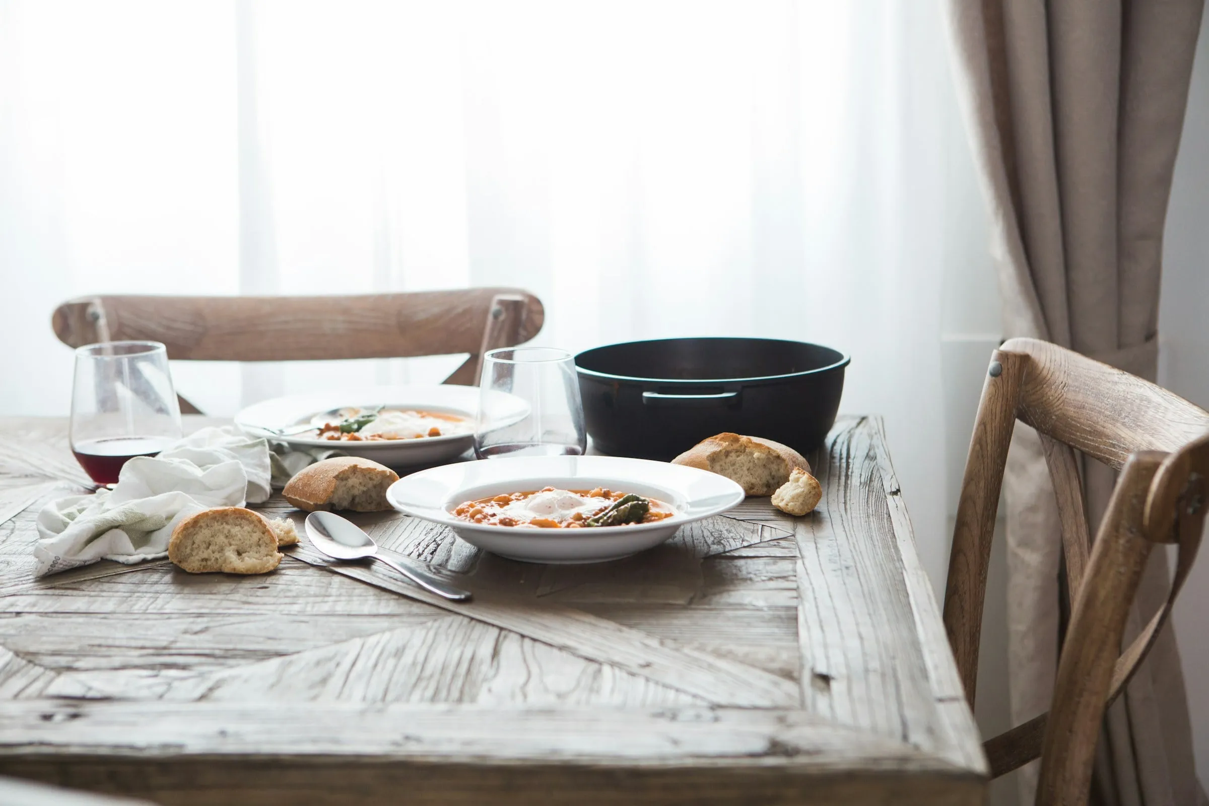 Sopa caseira servida em louça rústica, com pão e vinho