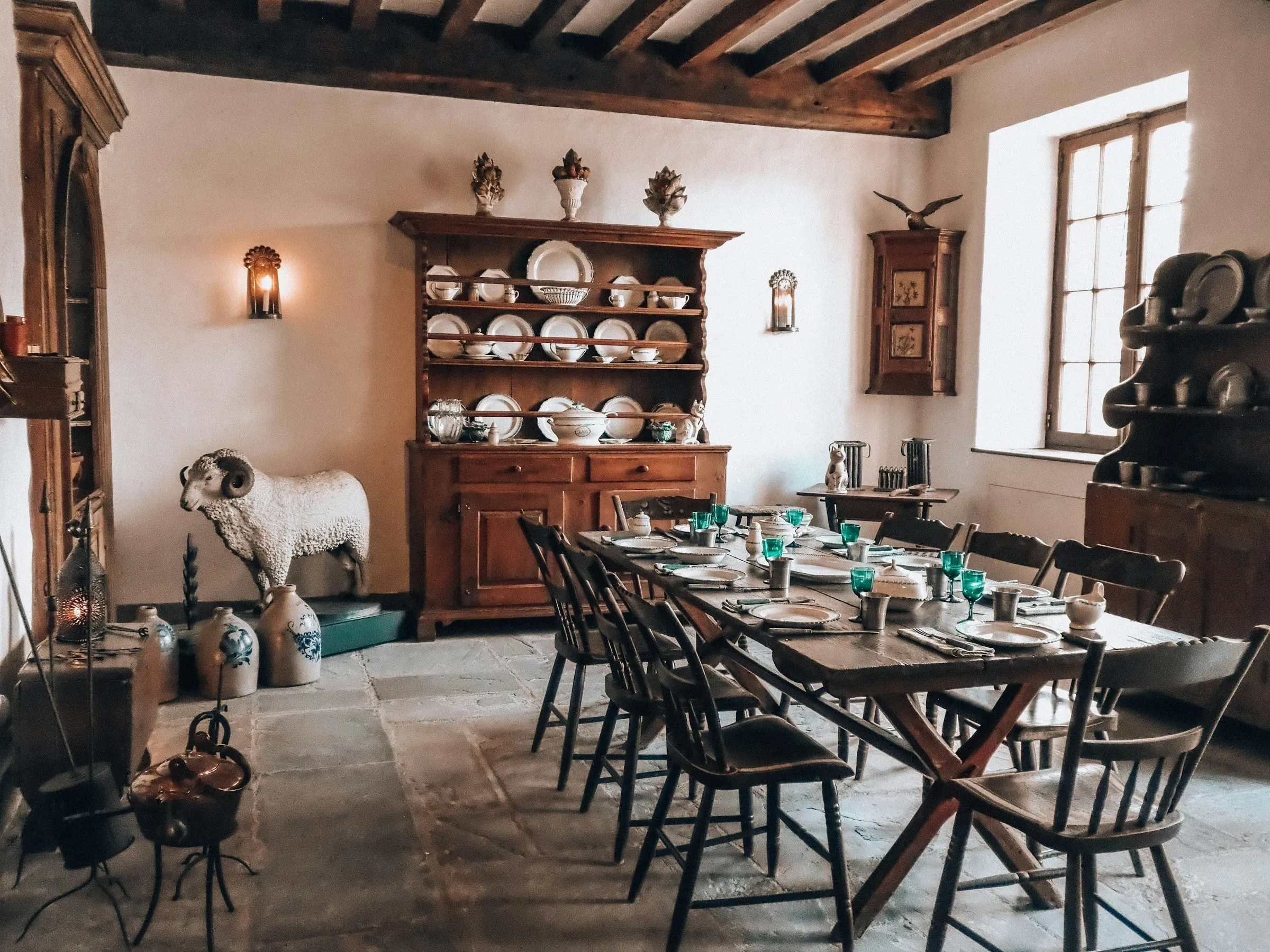 Salão rústico do restaurante, com mesa comprida e cristaleira de louças